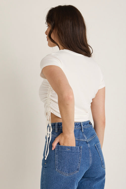Model wears a white rib top with jeans