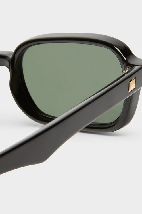 Front-facing view of rectangular sunglasses with a glossy black frame and green-tinted lenses. The slim silhouette features softly rounded corners for a modern take on a retro classic.