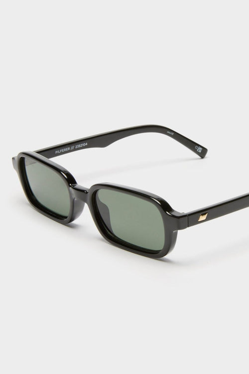 Front-facing view of rectangular sunglasses with a glossy black frame and green-tinted lenses. The slim silhouette features softly rounded corners for a modern take on a retro classic.
