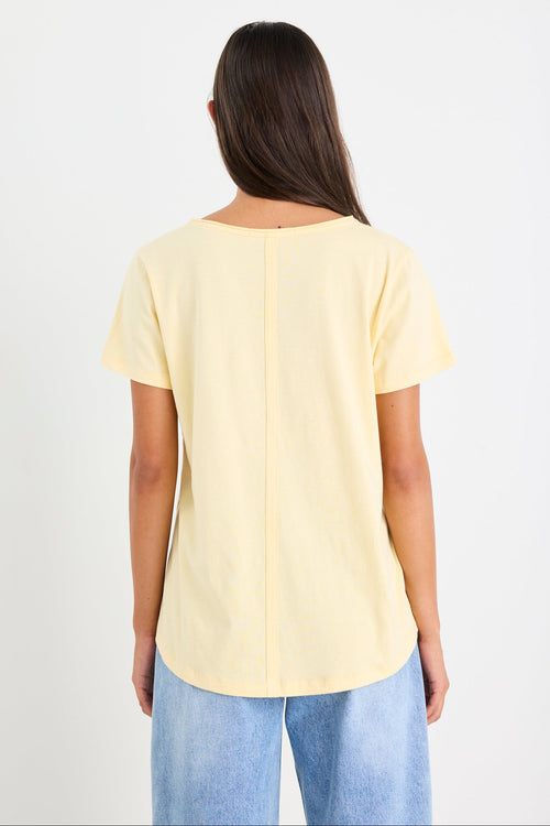 Woman wearing a yellow v neck tee and blue jeans