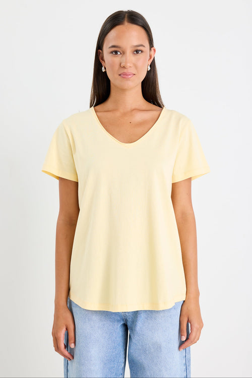 Woman wearing a yellow v neck tee and blue jeans