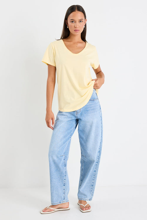 Woman wearing a yellow v neck tee and blue jeans