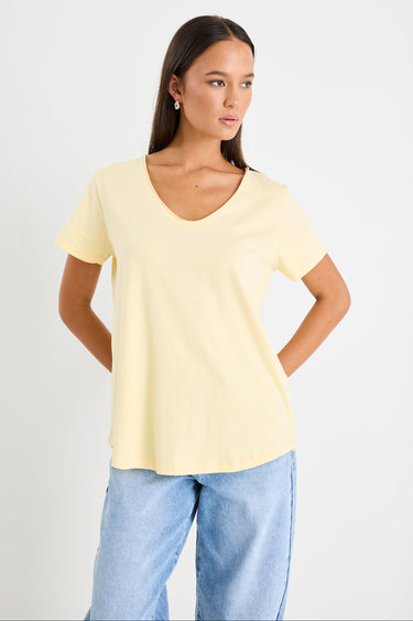 Woman wearing a yellow v neck tee and blue jeans