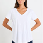 Woman wearing a white v neck top and dark blue jeans