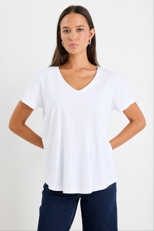 Woman wearing a white v neck top and dark blue jeans