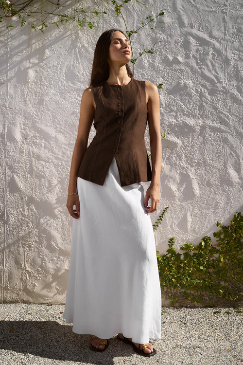 model wears a brown linen vest with white skirt