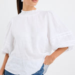 model wears a white linen blouse with dark blue jeans