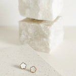 A pair of gold-toned stud earrings shaped like small flowers, featuring a pearlescent centre framed by a polished gold outline for a soft, elegant finish