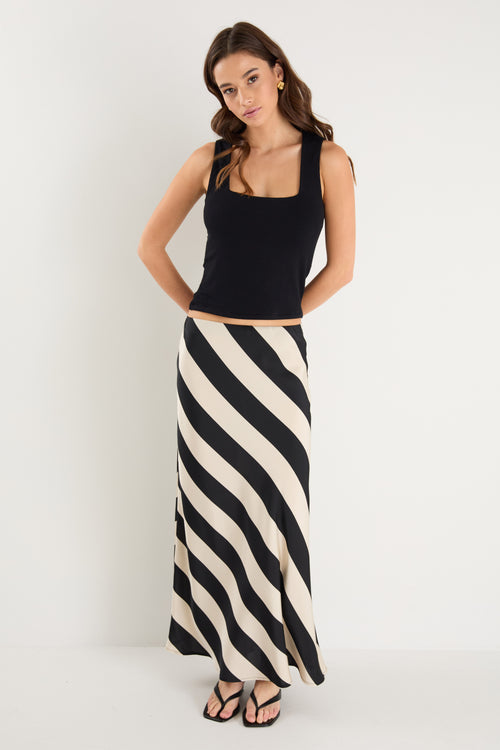 model wears a black and white stripe maxi skirt with a black tank top 