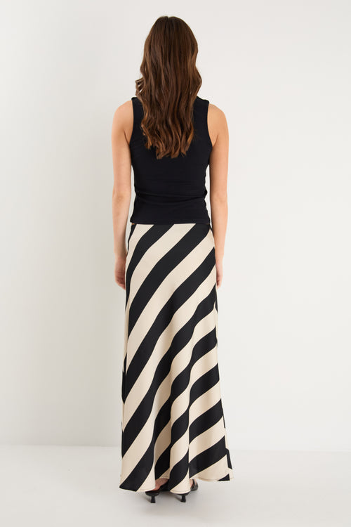 model wears a black and white stripe maxi skirt with a black tank top 
