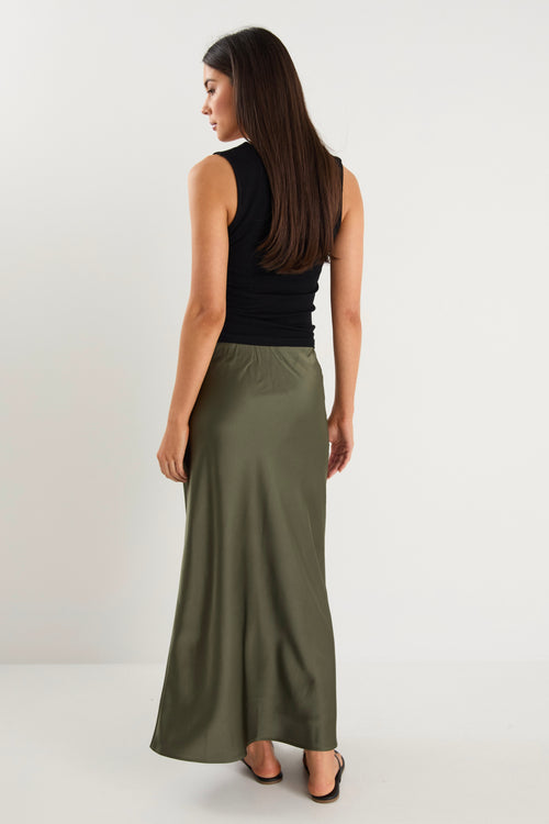 the model wears a khaki green maxi skirt with a black tank top