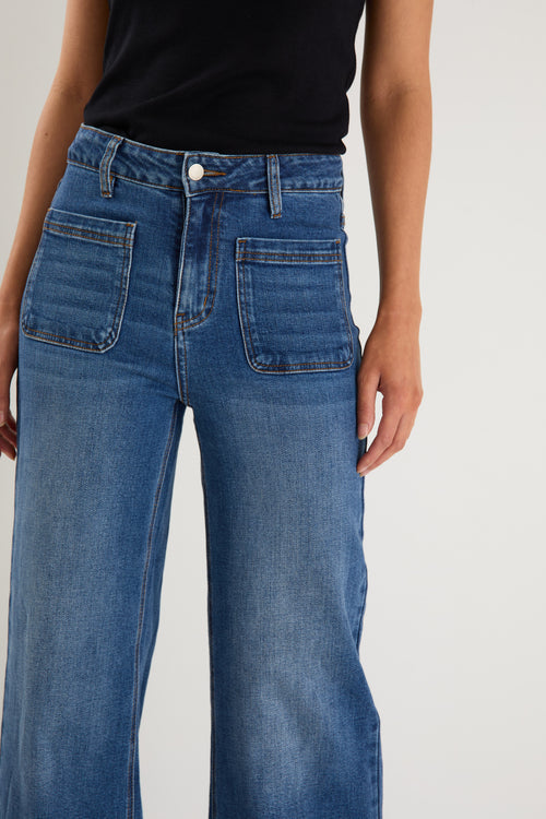 model wears  dark blue wide leg jean with a black tank top