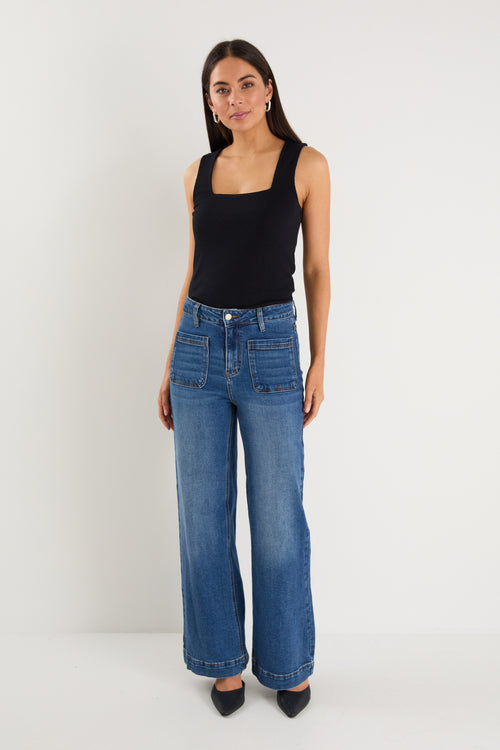 model wears  dark blue wide leg jean with a black tank top