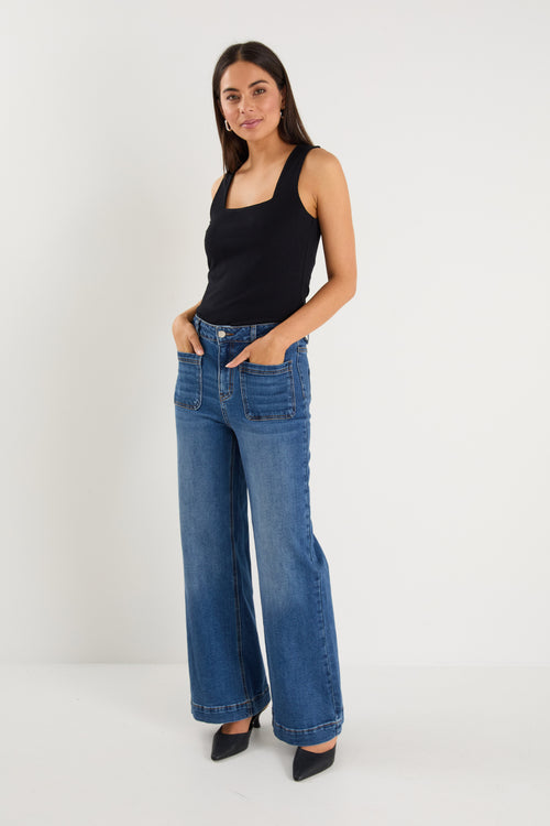 model wears  dark blue wide leg jean with a black tank top