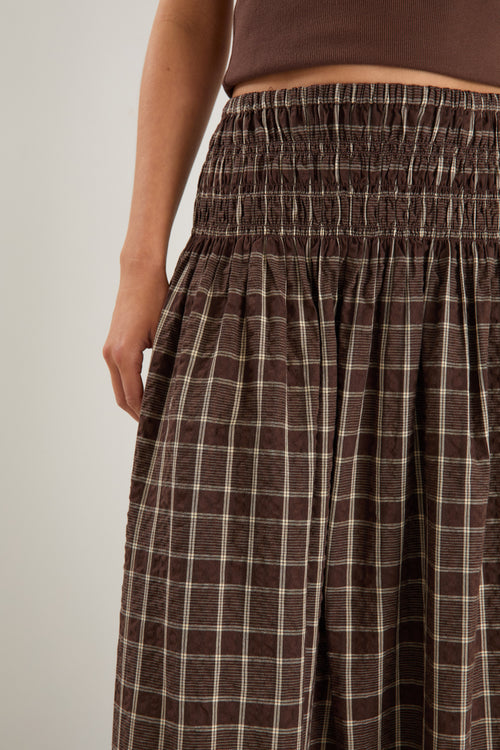 model wears a brown and beige check maxi skirt with a brown tank top