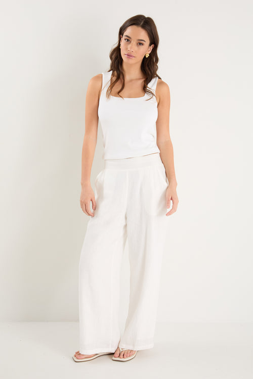 Woman wearing white pants and white top with gold accessories