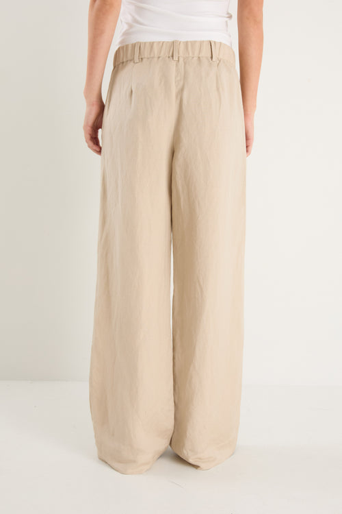 Beige wide-leg pants worn by a person on a white background