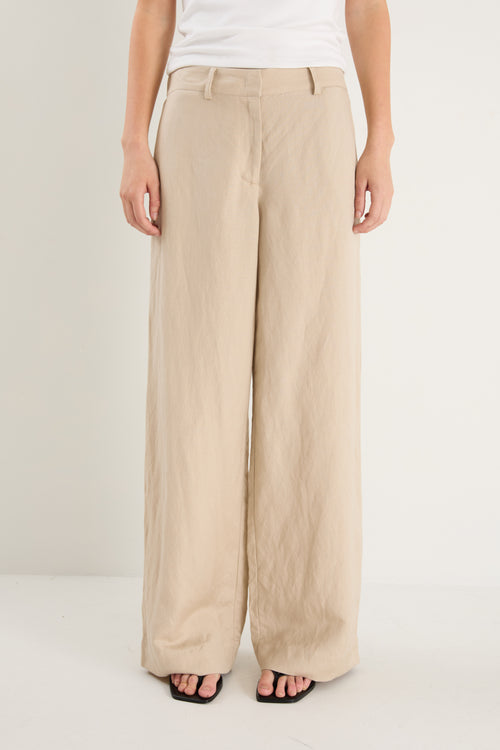 Beige wide-leg pants worn by a person on a white background