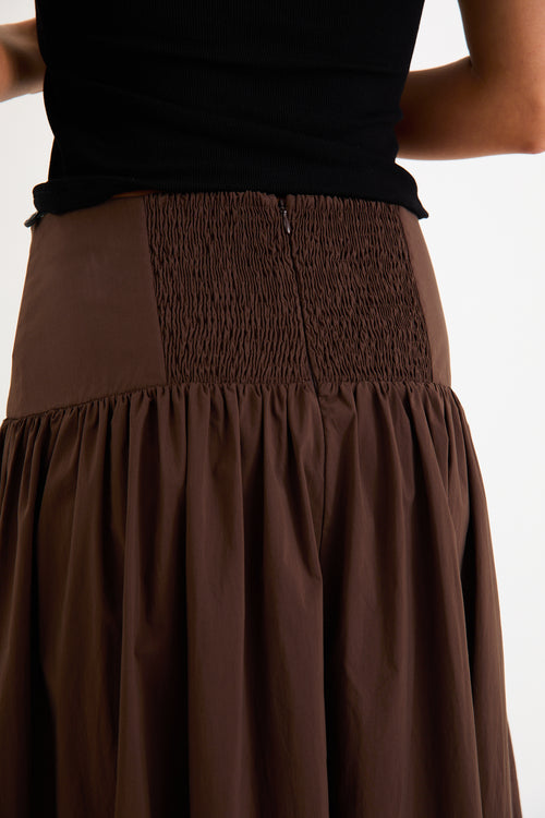 Model wearing a chocolate brown tiered maxi skirt with a flat waistband and shirred back
