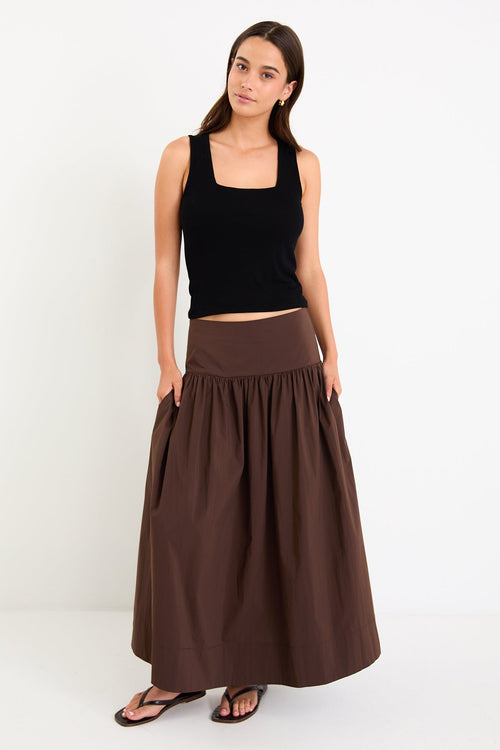 Model wearing a chocolate brown tiered maxi skirt with a flat waistband and shirred back