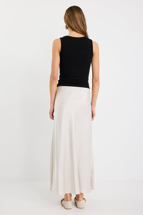 Woman wearing a pearl satin bias-cut maxi skirt with an elastic waistband, styled with a black tank top.