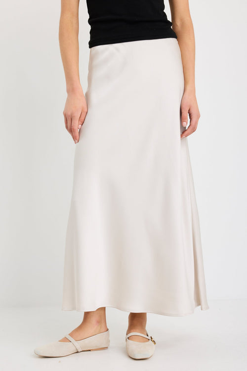 Woman wearing a pearl satin bias-cut maxi skirt with an elastic waistband, styled with a black tank top.