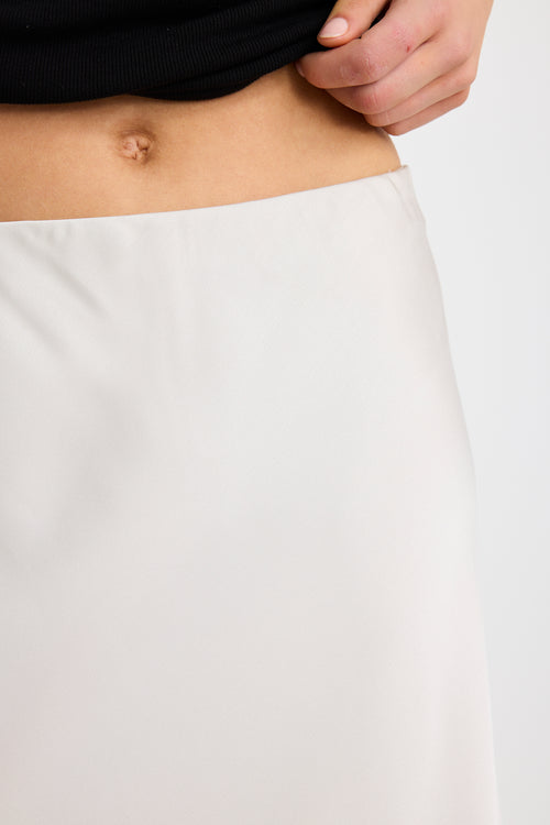 Woman wearing a pearl satin bias-cut maxi skirt with an elastic waistband, styled with a black tank top.