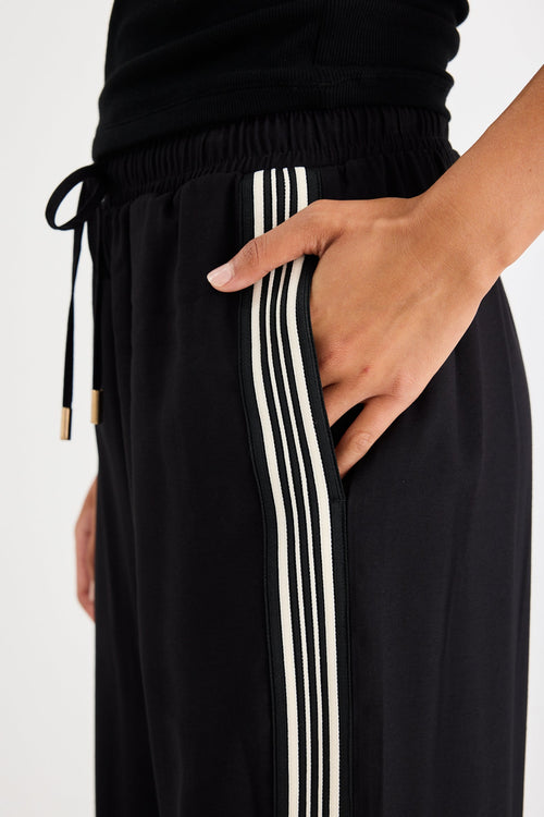 Woman wearing black pants with a side stripe and a black tank top