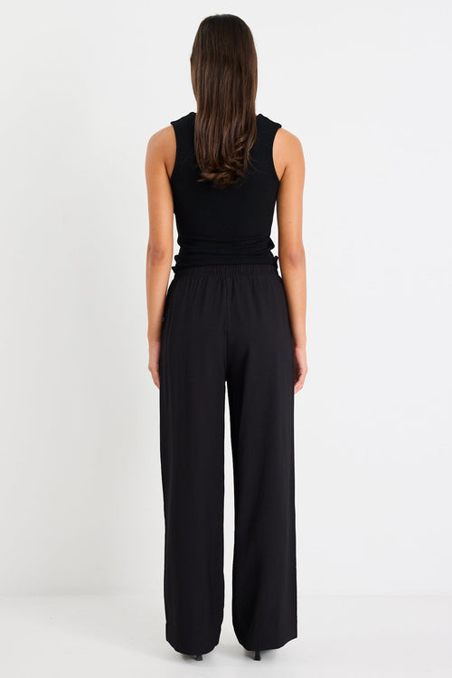 Woman wearing black pants with a side stripe and a black tank top