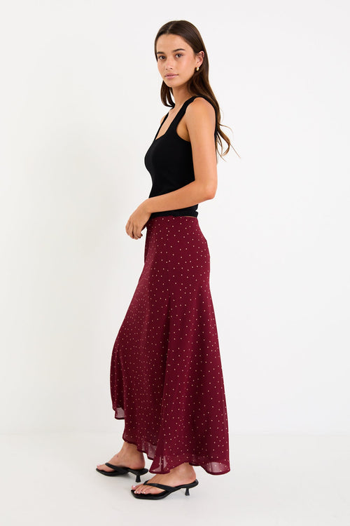 Model wearing a burgundy polka dot satin midi skirt with a bias-cut silhouette and a soft drape