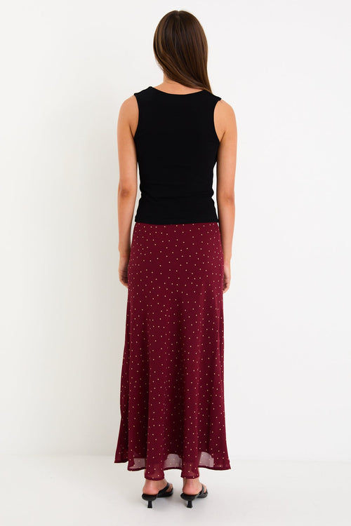 Model wearing a burgundy polka dot satin midi skirt with a bias-cut silhouette and a soft drape
