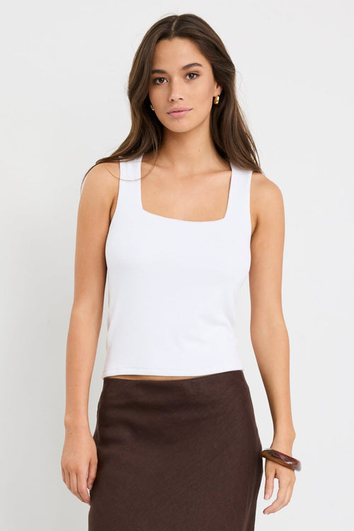 model wearing white tank and brown skirt