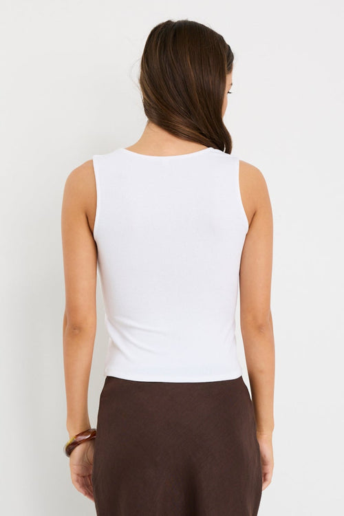 model wearing white tank and brown skirt