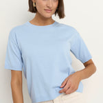 model wears a light blue knit t-shirt with ecru wide leg jeans