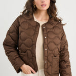 Woman wearing a brown quilted jacket on a white background