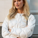 Woman wearing a white puffer jacket with a neutral background