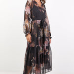Woman wearing a floral dress with sheer overlay on a white background