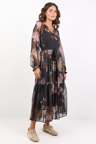 Woman wearing a floral dress with sheer overlay on a white background