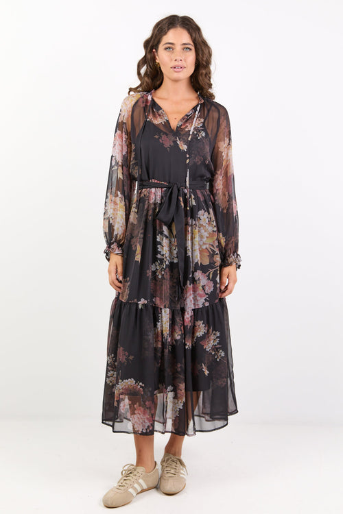 Woman wearing a floral dress with a sheer overlay on a white background