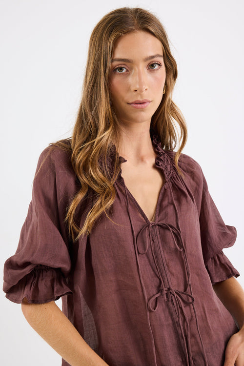 Woman wearing a brown blouse with a plain background