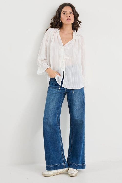Woman wearing a white blouse and blue jeans on a white background