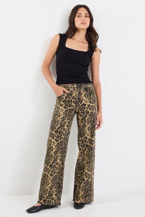 Woman wearing a black top and leopard print pants on a white background