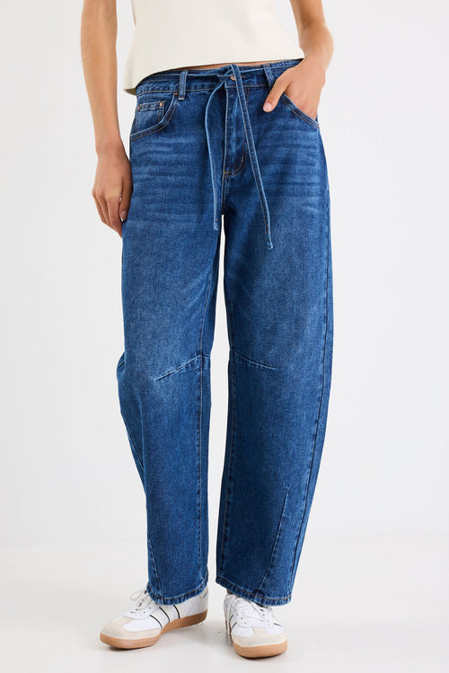 Person wearing blue jeans and white sneakers on a white background