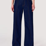 Person wearing dark blue wide-leg jeans on a white background