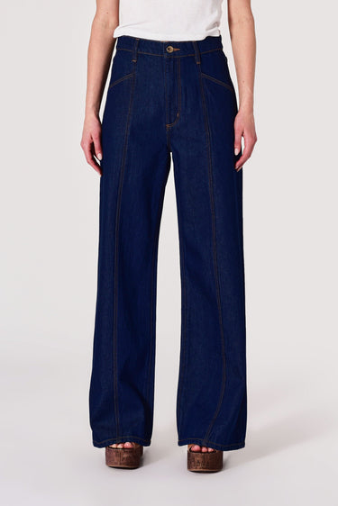 Person wearing dark blue wide-leg jeans on a white background