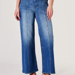 Person wearing blue jeans on a plain background