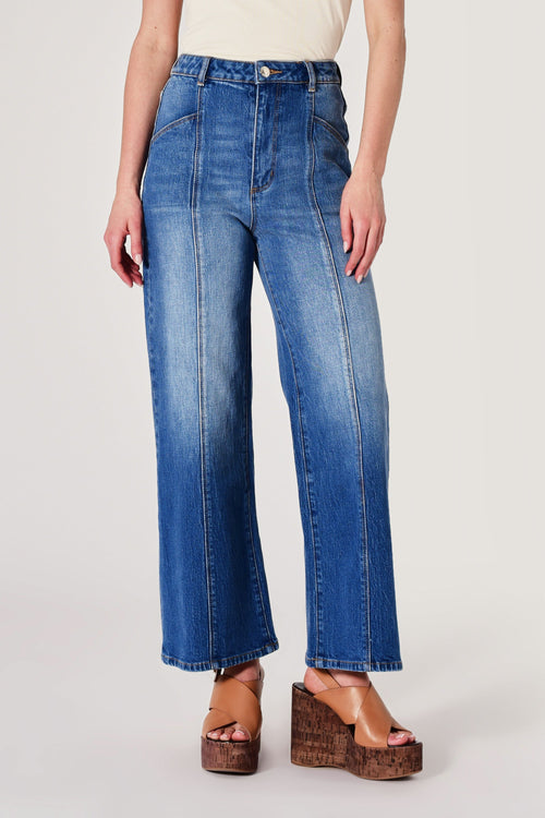 Person wearing blue jeans on a plain background