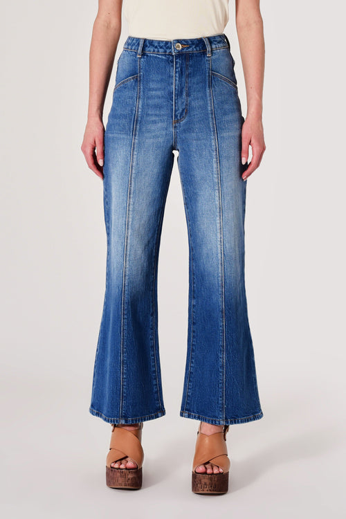 Person wearing blue flared jeans on a white background