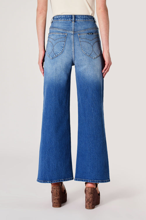 Person wearing blue wide-leg jeans on a white background