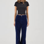 Woman wearing a black top and blue velvet pants on a white background